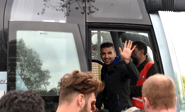 Un homme sourit en montant à bord d'un bus qui doit emmener des migrants sans abri durable dans des centres d'accueil et d'orientation, à Grande-Synthe, le 12 avril 2017