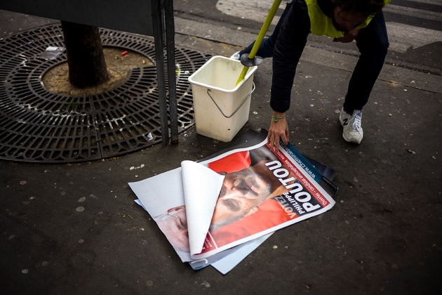 Une employée de France Affichage Plus colle une affiche de P.Poutou le 10 avril 2017 à Paris