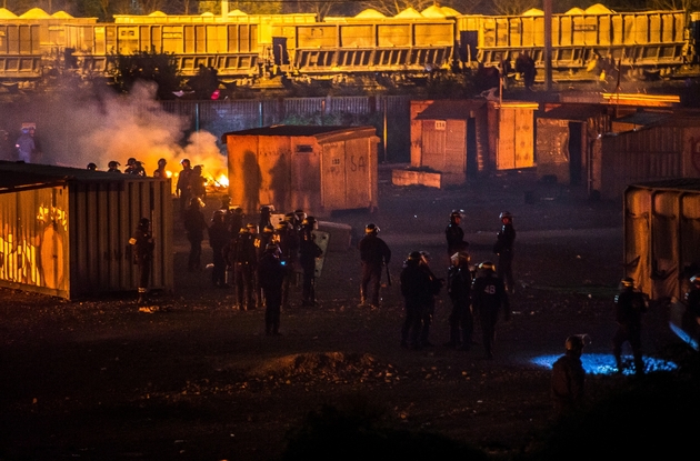 Des migrants evacuent le camp en feu, le 10 avril 2017 à Grande-Synthep