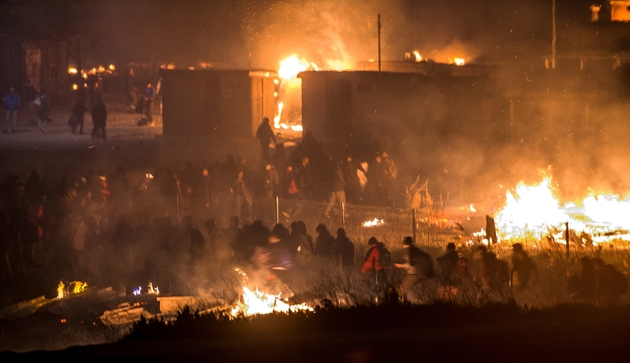 Des migrants evacuent le camp en feu, le 10 avril 2017 à Grande-Synthe